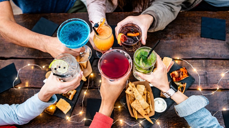 Aerial view of friends clinking cocktail glasses together.