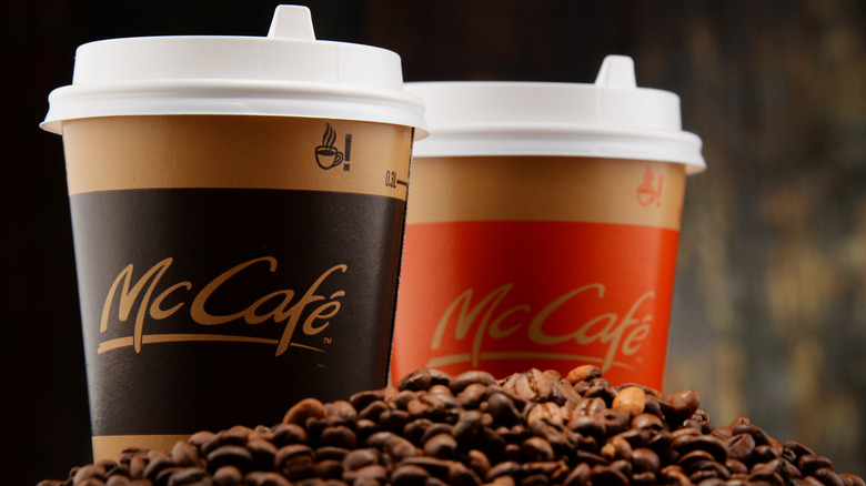 Two McDonald's McCafé coffee cups on coffee beans