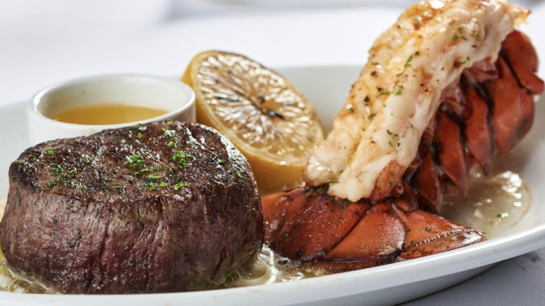 filet mignon with lobster tail on plate with lemon slice
