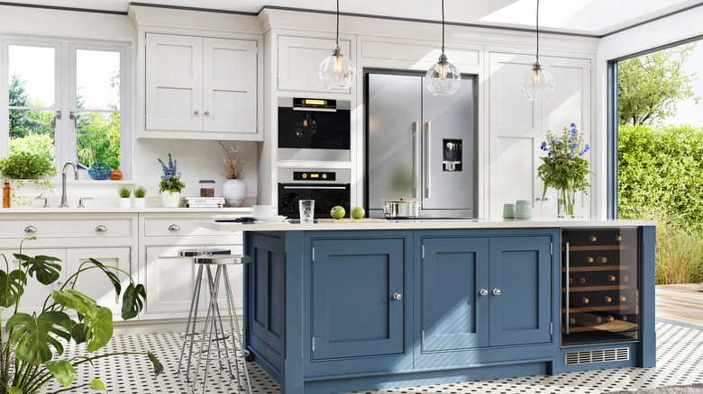 White kitchen with a blue island and stainless steel appliances