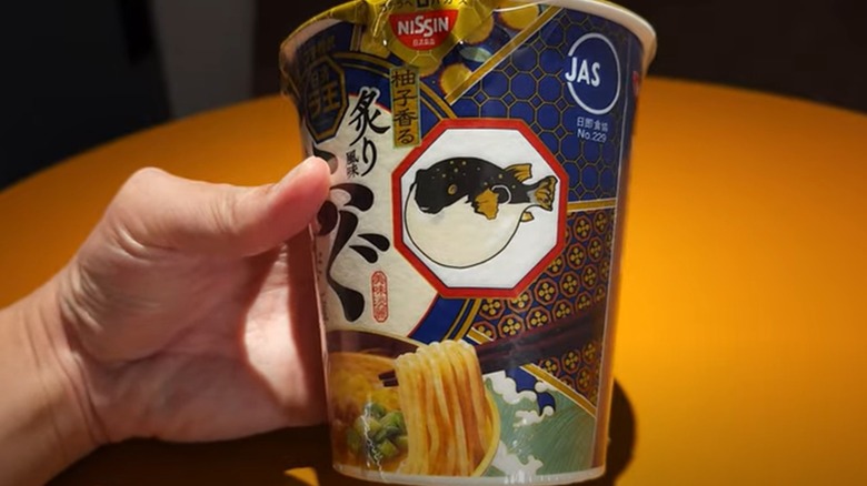 Person holding Nissin pufferfish fugu cup noodles