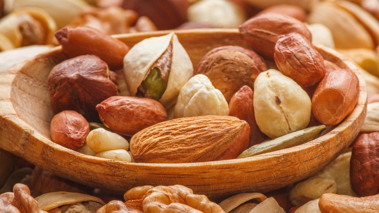 variety of nuts in and out of wooden spoon