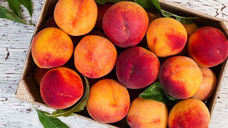 A wooden crate filled with fresh peaches