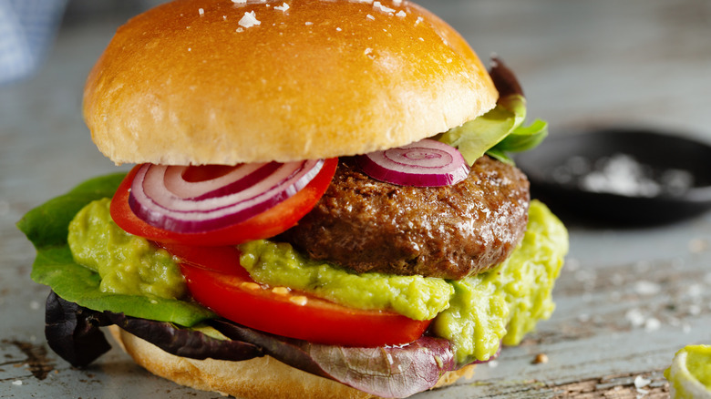 close up of classic hamburger with mashed avocado