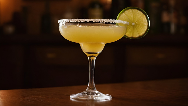A margarita in a glass garnished with a lime slice and salt rim.